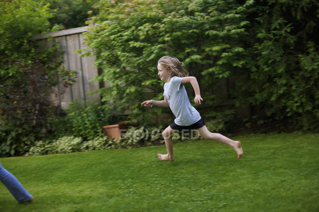 Vista lateral da menina correndo no quintal — Fotografia de Stock
