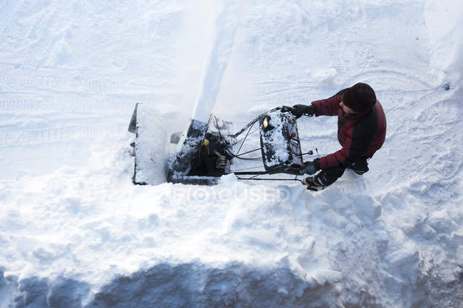 Vista superior del hombre usando un soplador de nieve - foto de stock