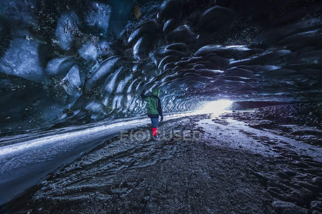 Homem olha para a entrada da caverna sob o gelo da geleira Canwell na Cordilheira do Alasca no inverno. Alaska, EUA — Fotografia de Stock