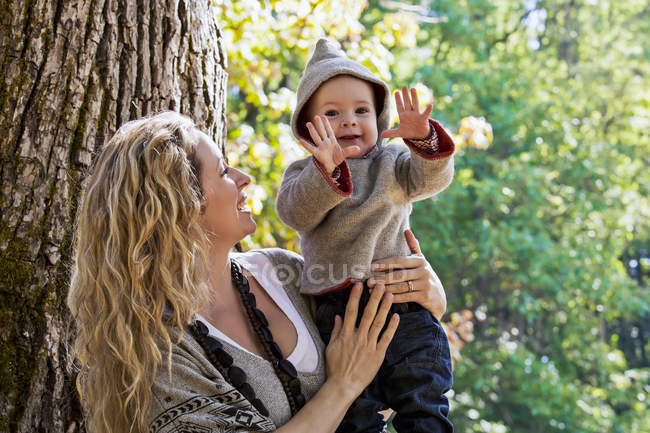 Madre sosteniendo hijo al aire libre en un parque en otoño - foto de stock