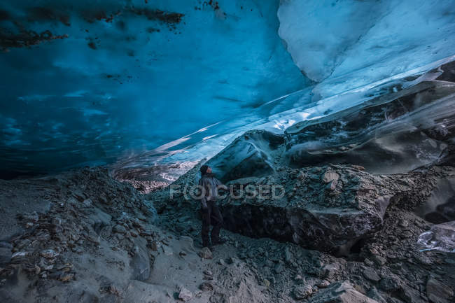 L'homme regarde la glace bleue translucide de la grotte de glace du glacier Canwell. Alaska, États-Unis d'Amérique — Photo de stock
