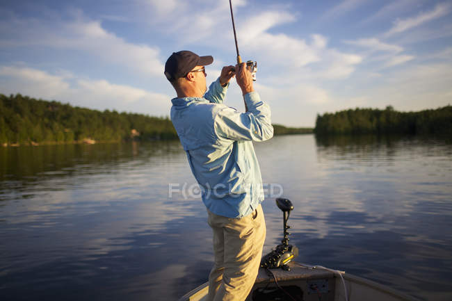 Вид ззаду рибалки з рибою на його лінії — стокове фото