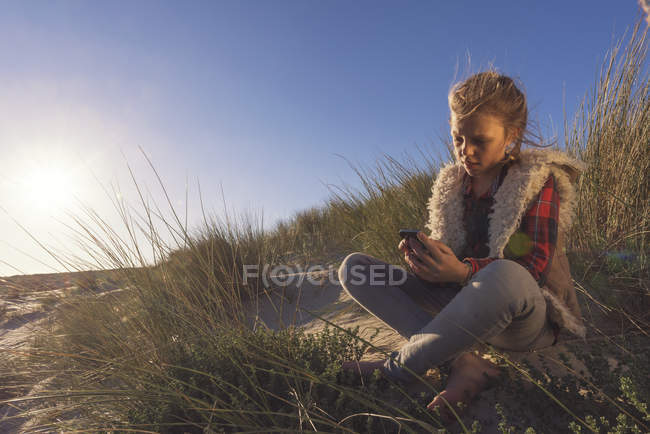 Joven niña se sienta en la arena - foto de stock
