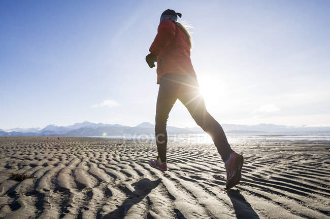 Une jeune femme fait du jogging sur la plage humide ; Homer, Alaska, États-Unis d'Amérique — Photo de stock
