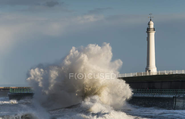 Welle bricht vor einem Leuchtturm — Stockfoto