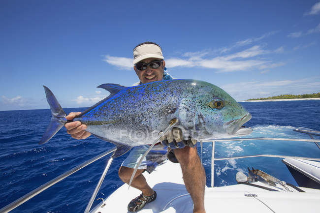 Fisherman on boat holding fresh caught Jackfish — Stock Photo