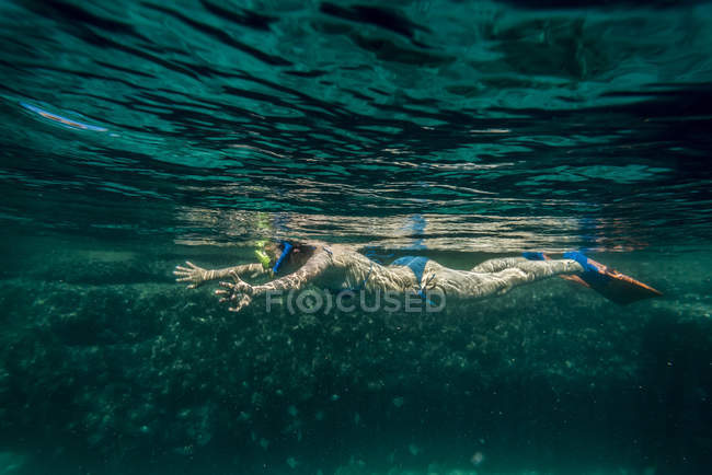 Vista laterale della donna che nuota sott'acqua con maschera da nuoto — Foto stock