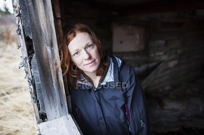 Portrait of a woman with red hair leaning against a wooden wall — Stock Photo