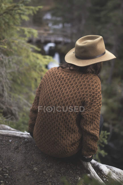 Mujer con sombrero posado en la cornisa con vistas al río en Girdwood, Southcentral Alaska
. - foto de stock