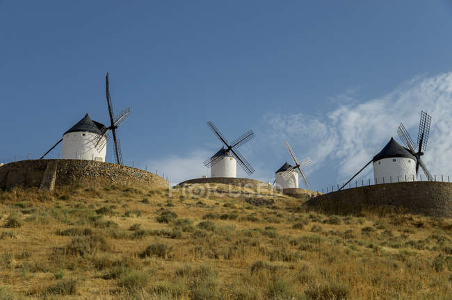 Moinhos de vento em uma linha contra um céu azul — Fotografia de Stock