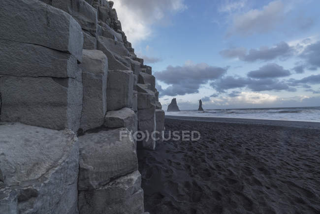 Columnar rocks line shore — Stock Photo