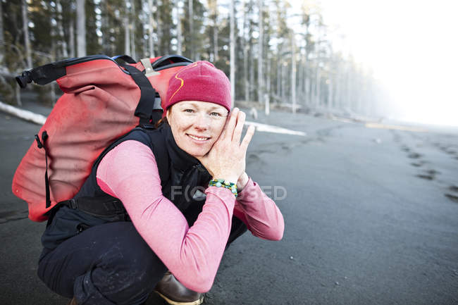 Woman crouching on the beach carrying backpack, Alaska, USA — Stock Photo
