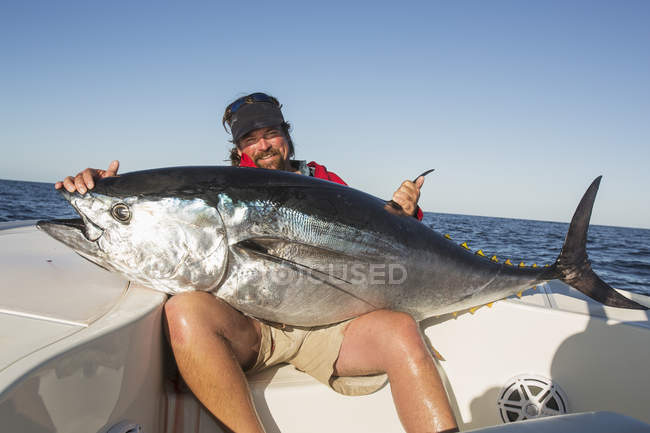 Pescador sostiene grandes peces frescos capturados en barco en el océano Atlántico. Cape Cod, Massachusetts, Estados Unidos de América - foto de stock