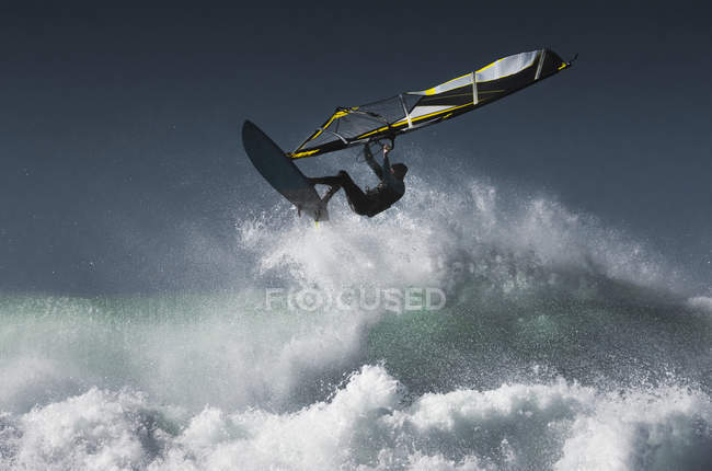 Planche à voile dans les airs au-dessus des vagues éclaboussantes ; Tarifa, Cadix, Andalousie, Espagne — Photo de stock