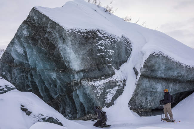 Deux hommes observent un gros morceau de glace au glacier Canwell en Alaska Range, Alaska, États-Unis — Photo de stock