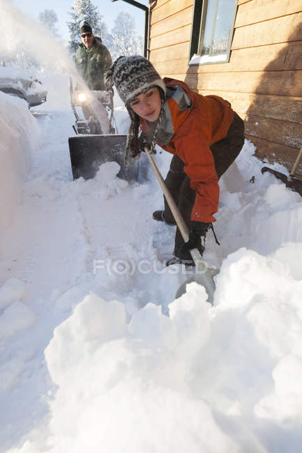 Un padre e una figlia che rimuovono la neve profonda a lato della loro casa; Homer, Alaska, Stati Uniti d'America — Foto stock