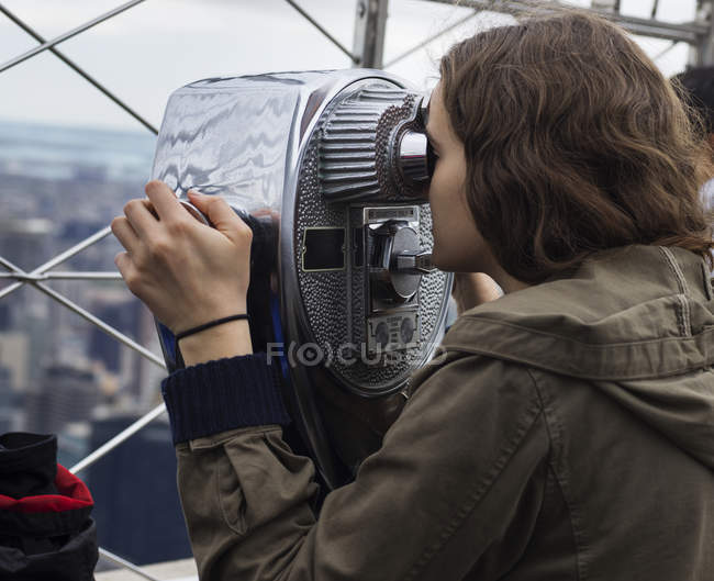 Woman looks through binoculars — Stock Photo