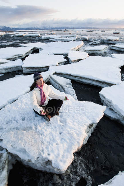 Жінка, що практикують медитацію на шматки льоду штабеліроваться проти коси Гомер, Аляска — стокове фото