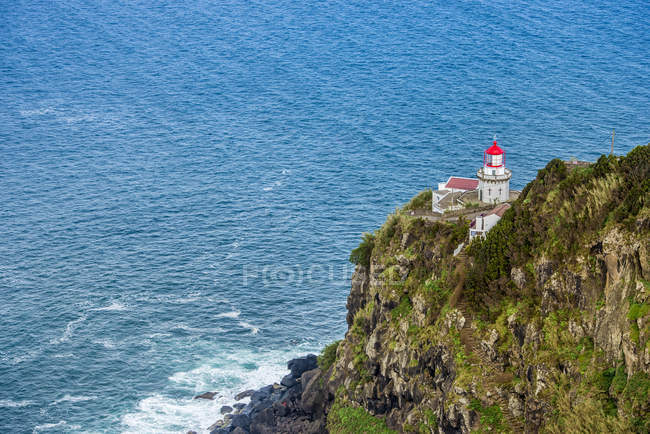 Lighthouse on rock with grass — Stock Photo