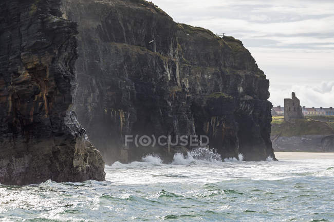 Dark straight cliffs with waves — Stock Photo