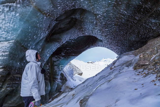 Una mujer joven observa el hielo expuesto del glaciar Castner en la cordillera de Alaska en invierno; Alaska, Estados Unidos de América - foto de stock