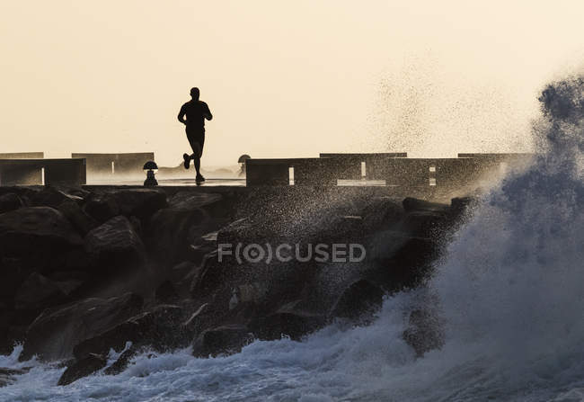 Людина біжить уздовж узбережжя — стокове фото