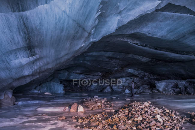 Homme se tient à l'intérieur d'une grotte de glace caverneuse au terminus du glacier Augustana en Alaska Range en hiver, Alaska, États-Unis d'Amérique — Photo de stock