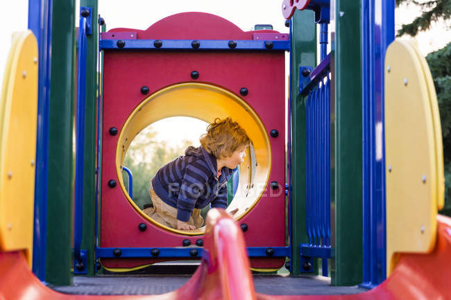 Menino brincando no playground da cidade ao pôr do sol — Fotografia de Stock