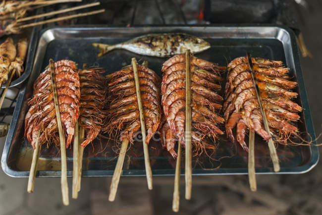 Some sticks with shrimp  on black plate at market — Stock Photo