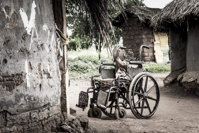 Cadeira de rodas fora de uma casa durante o dia; Uganda — Fotografia de Stock