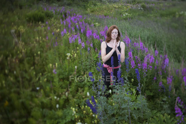 Femme faire du yoga dans une prairie avec des fleurs sauvages — Photo de stock