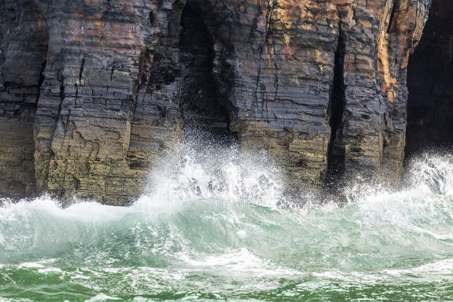 Хвилі врізаються в скелі — стокове фото