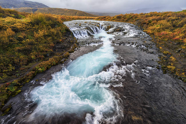 Cascada y agua corriente en un río - foto de stock