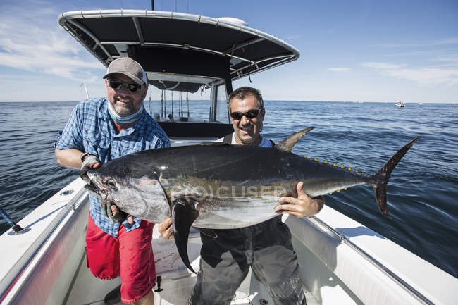 Два кавказьких рибалки тримають блакитний фінішний тунець на човні — стокове фото