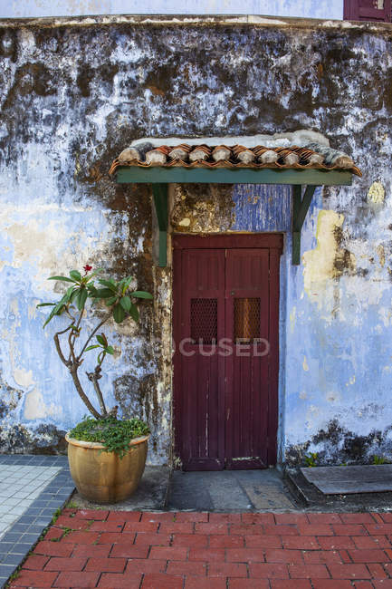 Porte rouge fanée se trouve entouré par un mur bleu altéré dans le centre-ville georgetown, Penang, Malaisie — Photo de stock