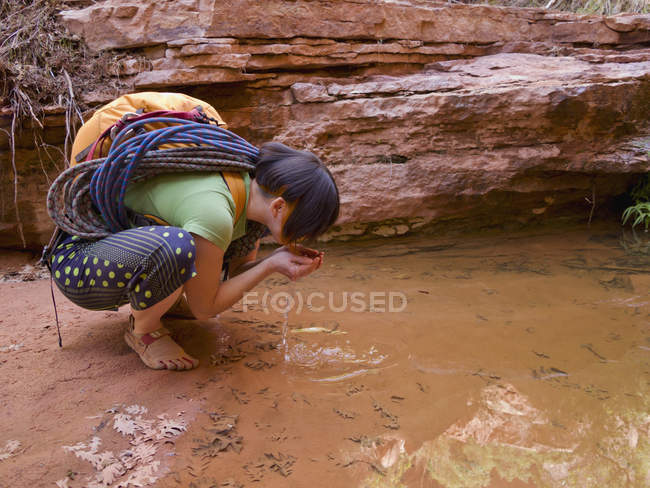 Avventuriera donna che beve dall'oasi desertica. Hanksville, Utah, Stati Uniti — Foto stock