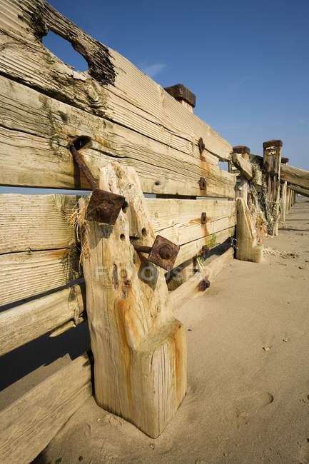 Cerca de madera en la playa bajo el cielo azul - foto de stock