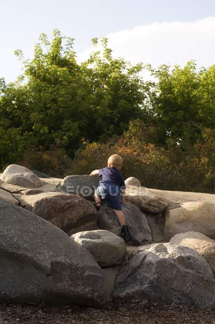 Вид сзади на молодого кавказского мальчика, стоящего на скалах на природе — стоковое фото