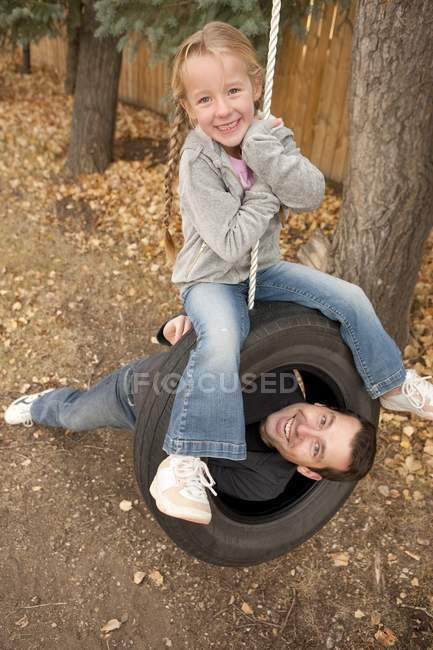 Happy father and daughter on tire swing — Stock Photo