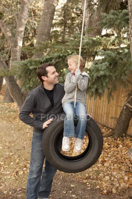 Батько штовхає дочку на гойдалці шин — стокове фото
