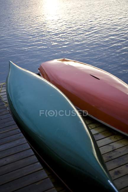 Lago de los Bosques, Ontario, Canadá; Canoas en muelle de madera sobre el agua - foto de stock