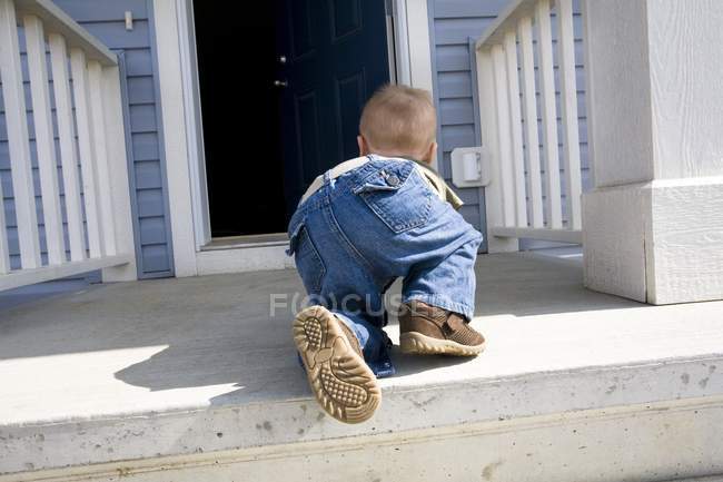 Visão traseira da criança rastejando para a porta aberta — Fotografia de Stock