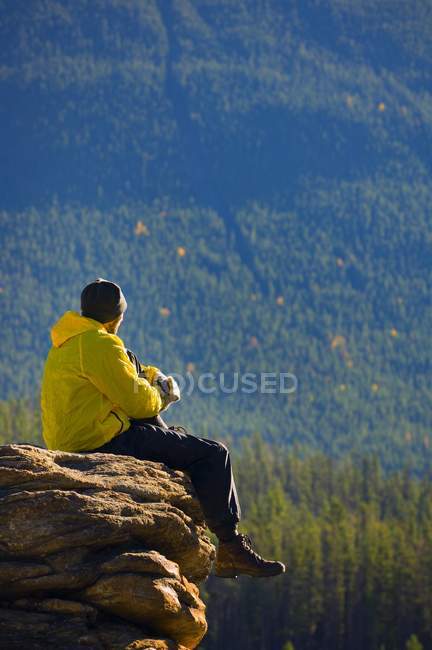 Hombre sentado en la montaña - foto de stock