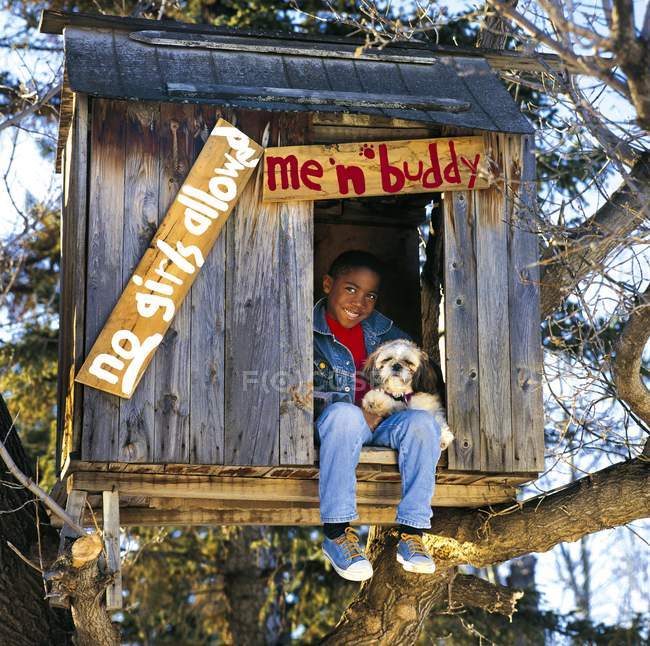 Garçon traînant dans la cabane dans les arbres avec chien — Photo de stock