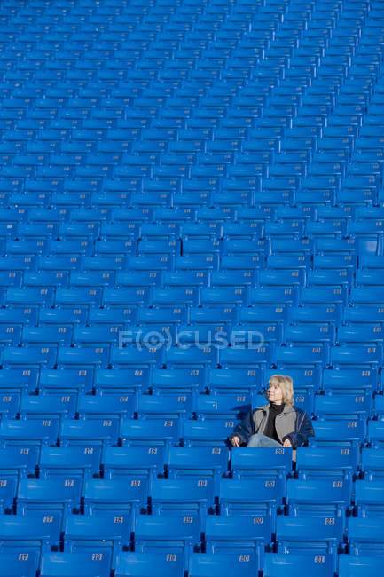Взрослая белая женщина, сидящая одна на пустом стадионе — стоковое фото