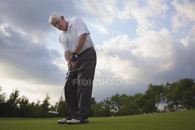 Старший білий чоловік грає в гольф на курсі — стокове фото