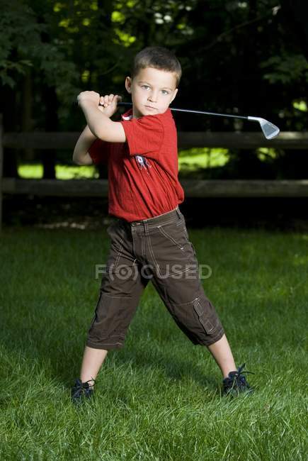 Jovem caucasiano menino com clube de golfe no curso — Fotografia de Stock