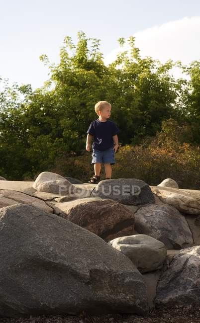 Giovane ragazzo caucasico in piedi su rocce a natura — Foto stock