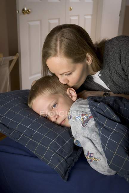 Біла мати прокидається сина, цілуючись у спальні — стокове фото