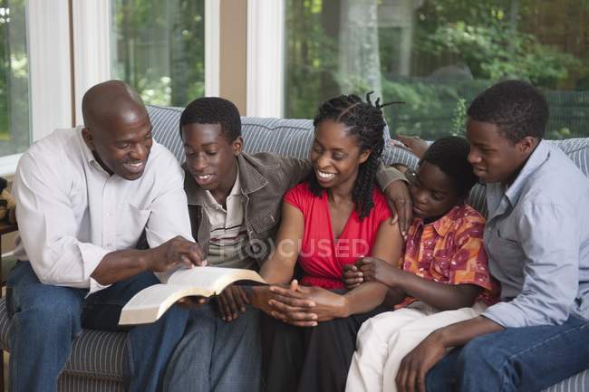 Famille chrétienne afro-américaine lecture de la Bible à la maison — Photo de stock